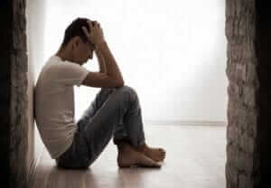 man sitting against the wall with a headache has heroin addiction