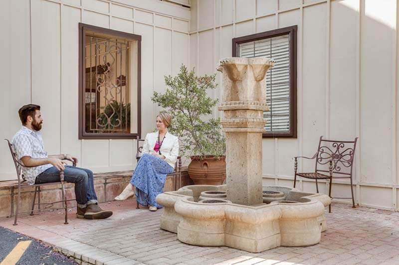 Two people sitting outside on patio with fountain at Santé