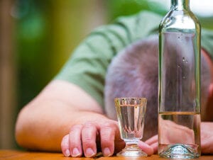 Man laying on table after drinking shots needs alcohol rehab for sure