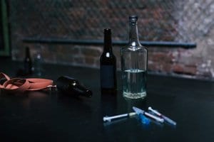 Various bottles and syringes rest on a table to represent polysubstance abuse