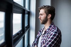 A man looks out a window wishing he was participating in recreational therapy