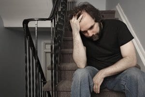 A man sits on a staircase thinking about his need for binge eating disorder treatment