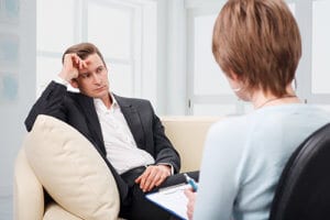 a man talks to a counselor during addiction treatment for executives