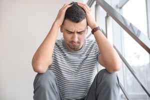 a man looks frustrated as he experiences sex addiction symptoms