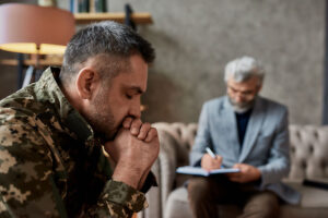 a person looks troubled as a therapist takes notes in a PTSD treatment program