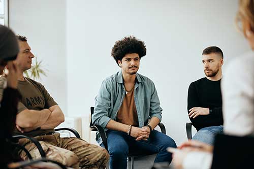 group of adults seated in a circle in an addiction treatment center as part of a 12-step program