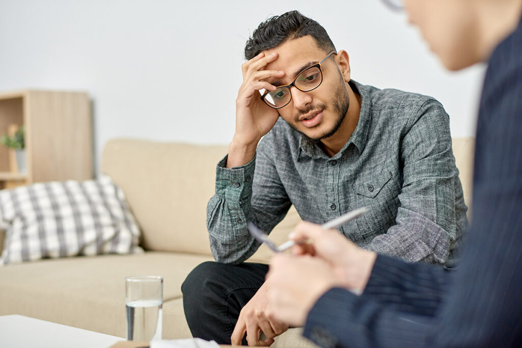 man with glasses sits on couch talking to therapist about why he should start an ADHD treatment program