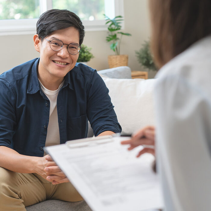 man with glasses smiles sitting across from therapist in his alcohol addiction treatment