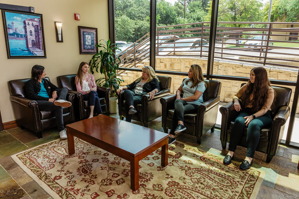 5 women sit together in chairs in a room discussing benefits of benzo addiction treatment programs