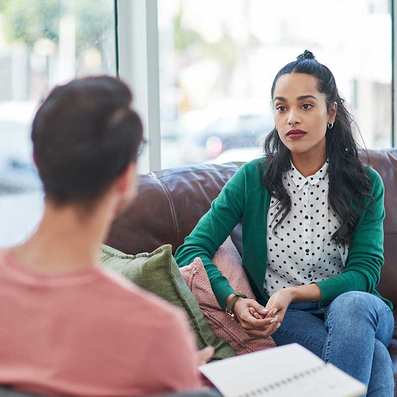 male therapist discuss cogntive-behavioral therapy with a female client in an office setting