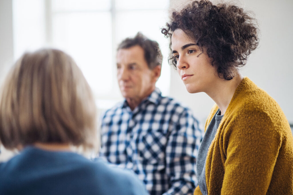 group of men and women seated in a circle and participating in a residential addiction treatment program.