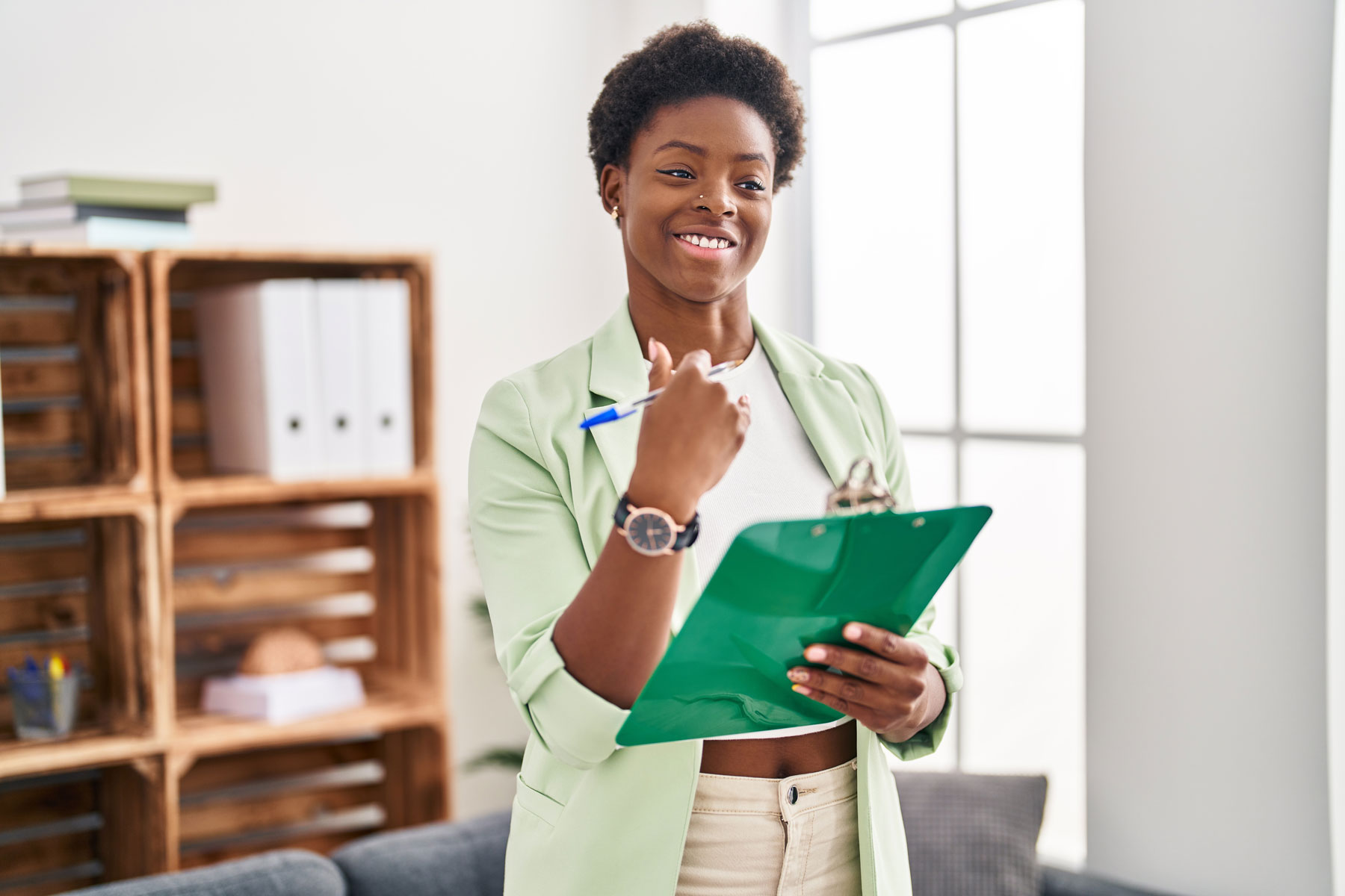 behavioral health care worker smiling and looking at clipboard as she explains the benefits of addiction treatment for professionals as a path to recovery