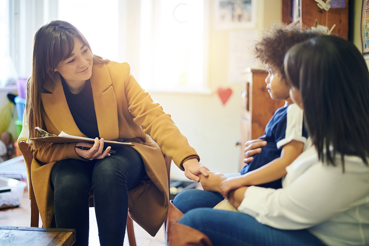 A woman in addiction recovery is being supported by having her child sit on her lap while visiting with a therapist.