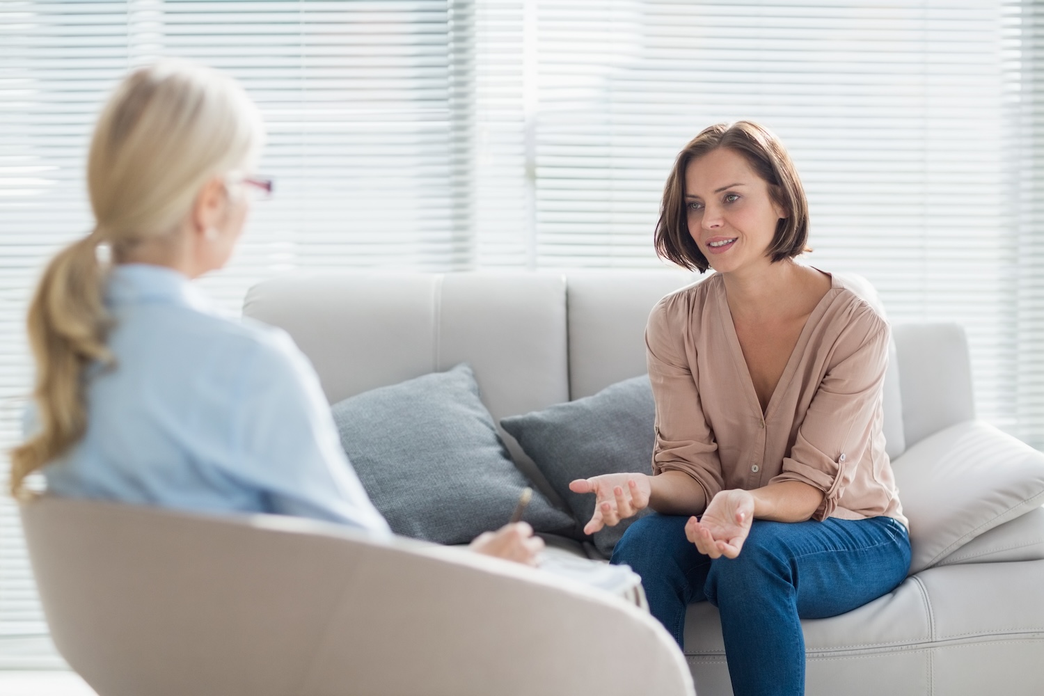 Woman sitting on a couch talking with a therapist during a counseling session.
