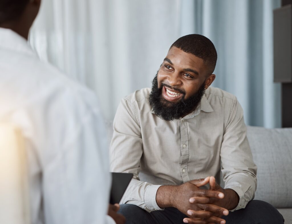 Man smiling and talking with a therapist during a one-on-one counseling session.