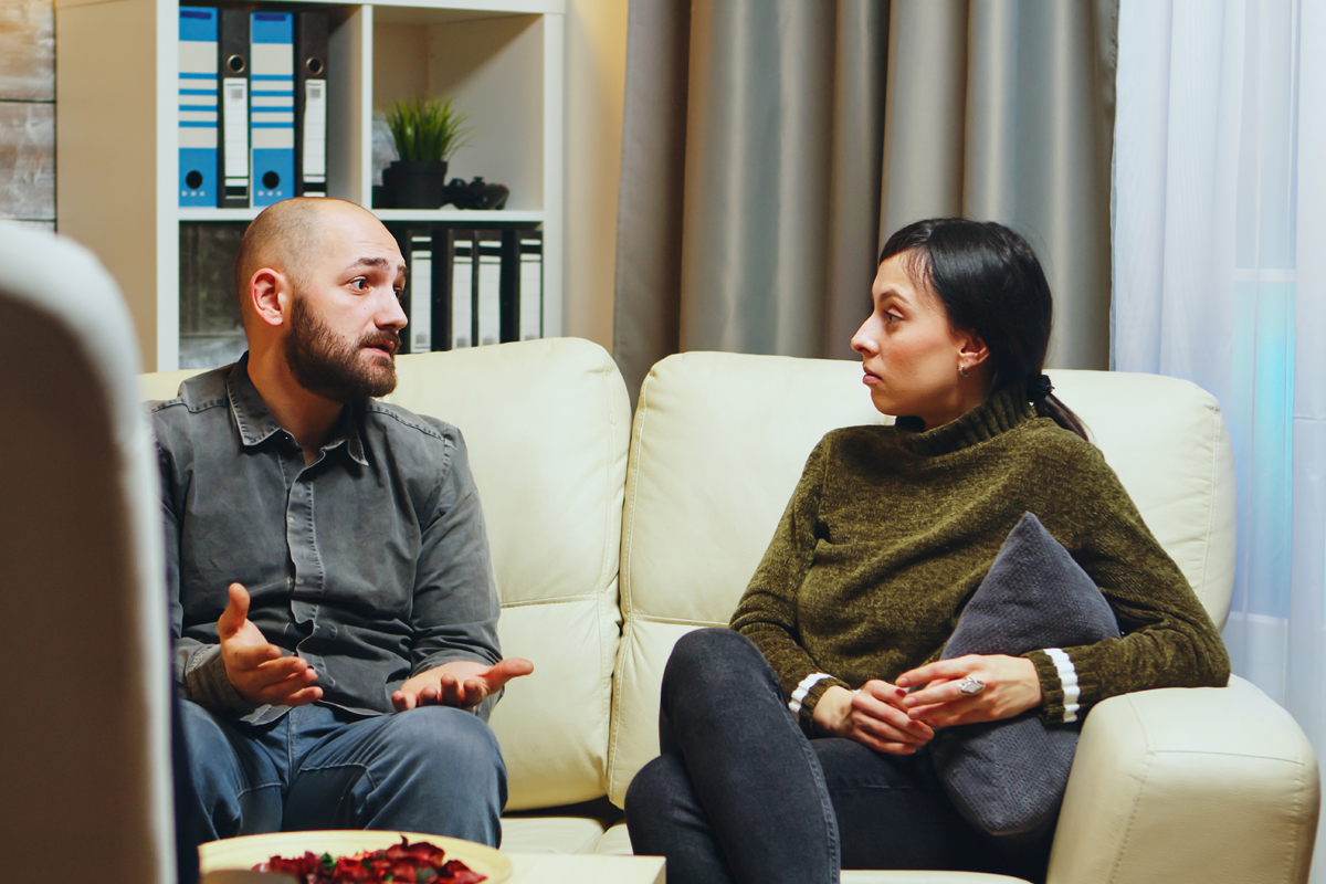 Man speaking to woman on couch